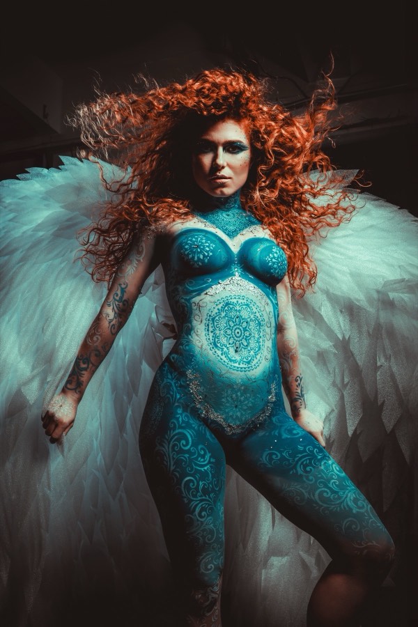 Bodypainting v modrozelené barevnosti s bílými křídly